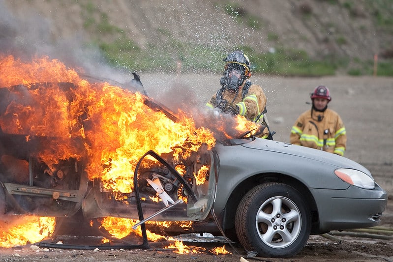 Car fire and fire fighters putting out the fire